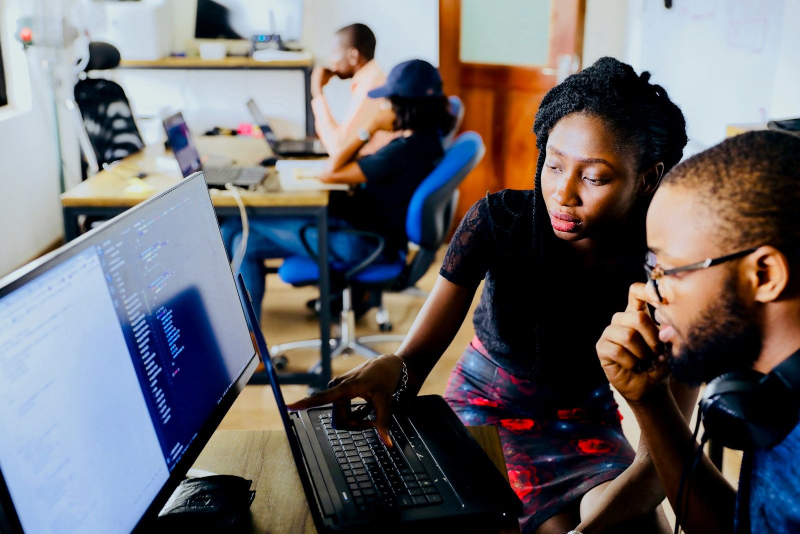 Two professionals collaborating over code on a screen in a tech office